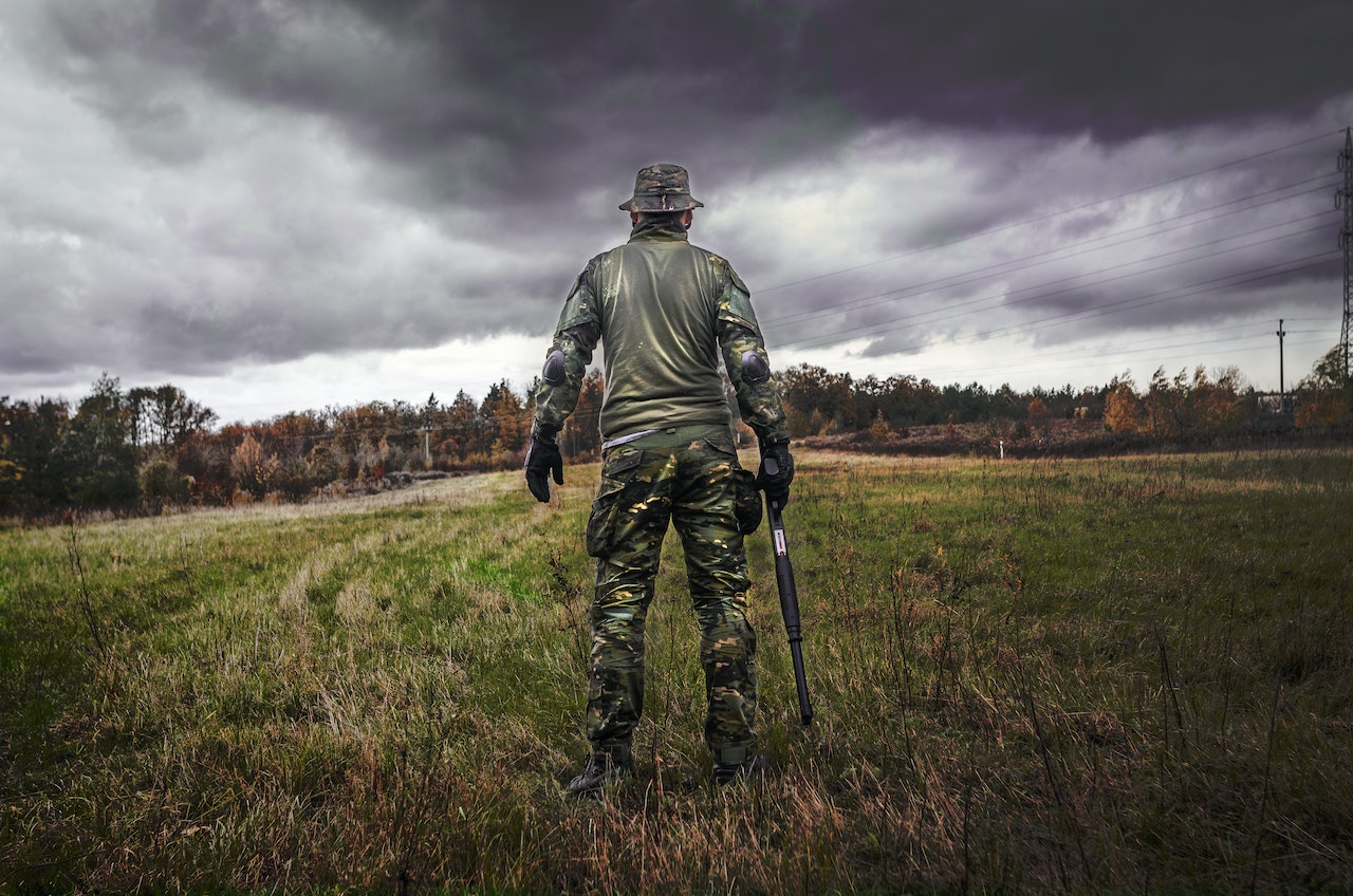 Man in Camouflage Suit Holding Shotgun | Veteran Car Donations