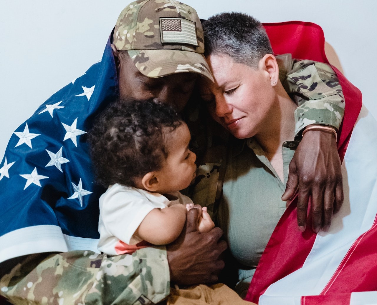 Army Couple Wrapped with an American Flag Sitting Beside Their Son